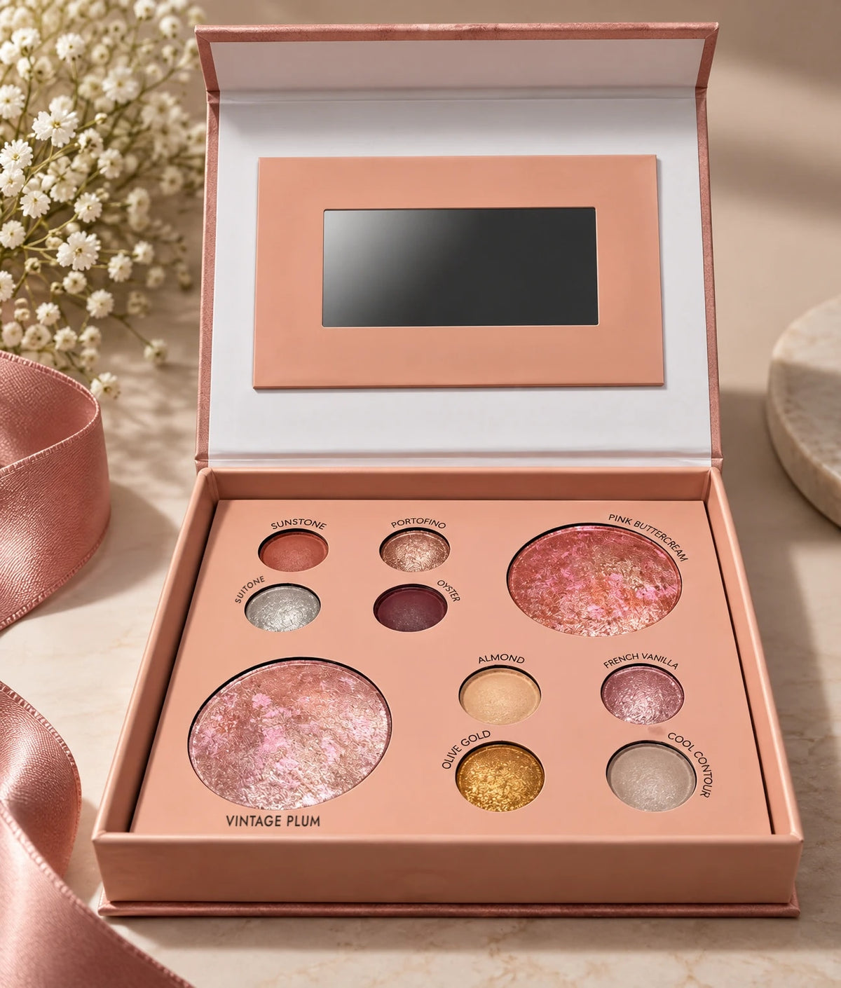 Riviera Rose palette open on a marble table with baby's breath and satin ribbon